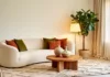 Tendances déco 2026 : Cloud Dancer, matières naturelles et courbes Salon aux murs blanc cassé avec canapé arrondi, tapis berbère et céramiques